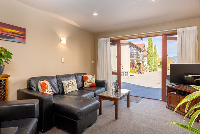 Living room and patio of ground floor 1 bedroom spa suite at Settlers Boutique Motel - Hanmer Springs accommodation